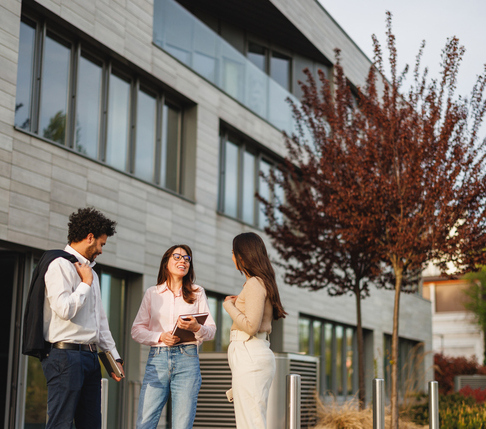 Tre studenti camminano nel campus davanti a un edificio in pietra, conversando tra loro.