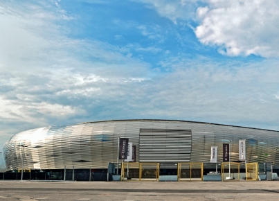 Moderno edificio aziendale con facciata curva e insegna visibile sotto un cielo nuvoloso.