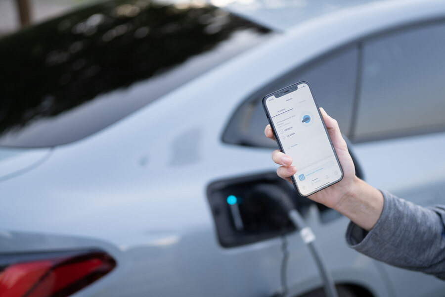 Veicolo in carica e proprietario dell'auto che controlla lo stato di ricarica tramite app