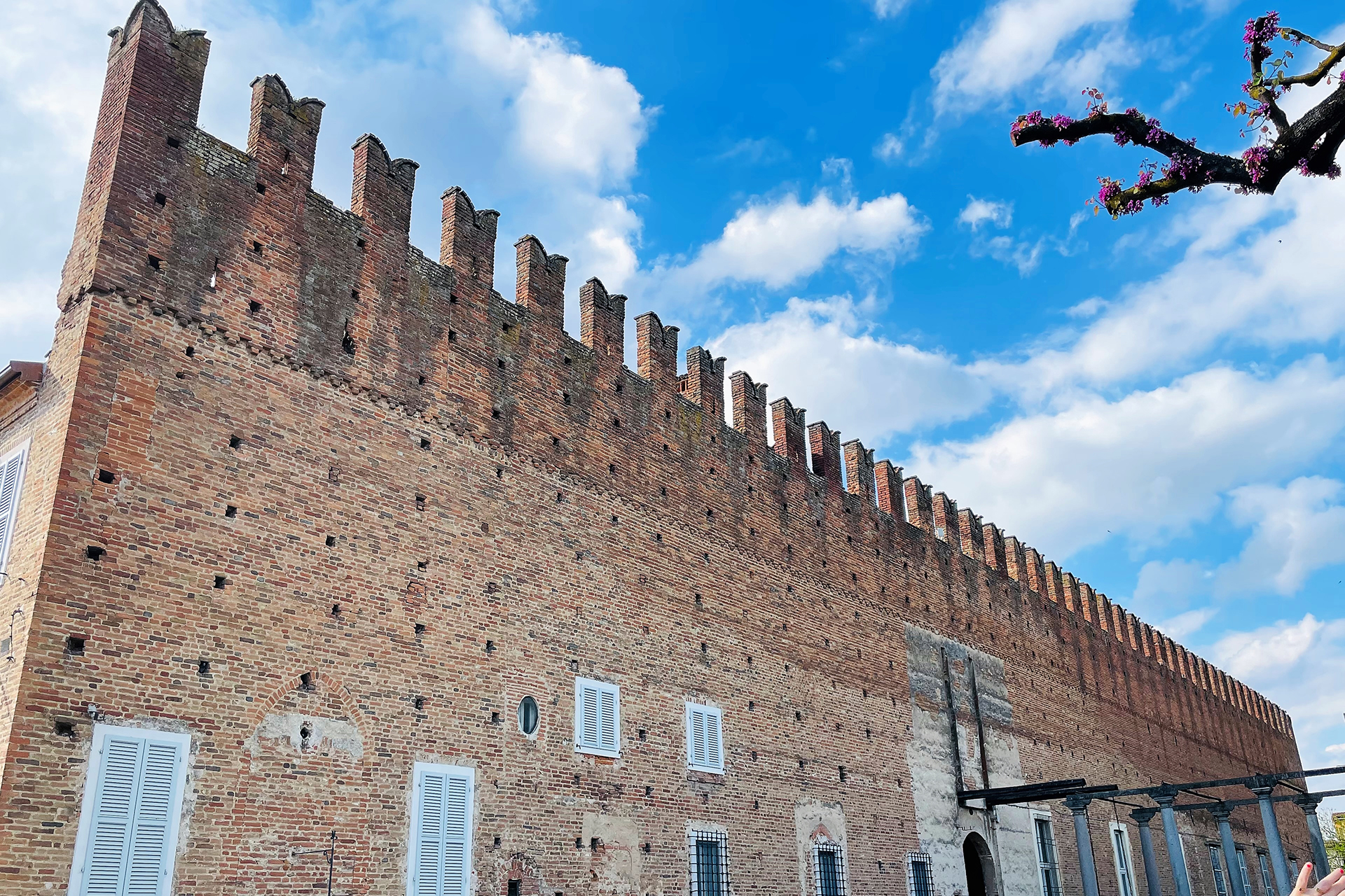 Castello di Belgioioso con mura in mattoni e cielo azzurro.