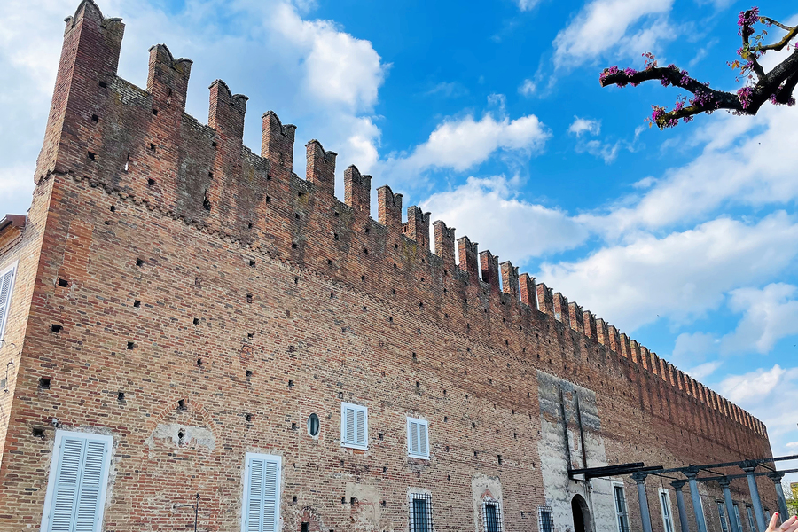 Castello di Belgioioso con mura in mattoni e cielo azzurro.