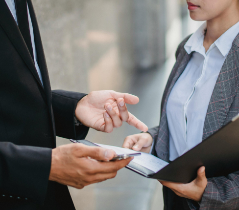 Collaborazione in ufficio: una persona consegna un documento mentre due professionisti parlano.