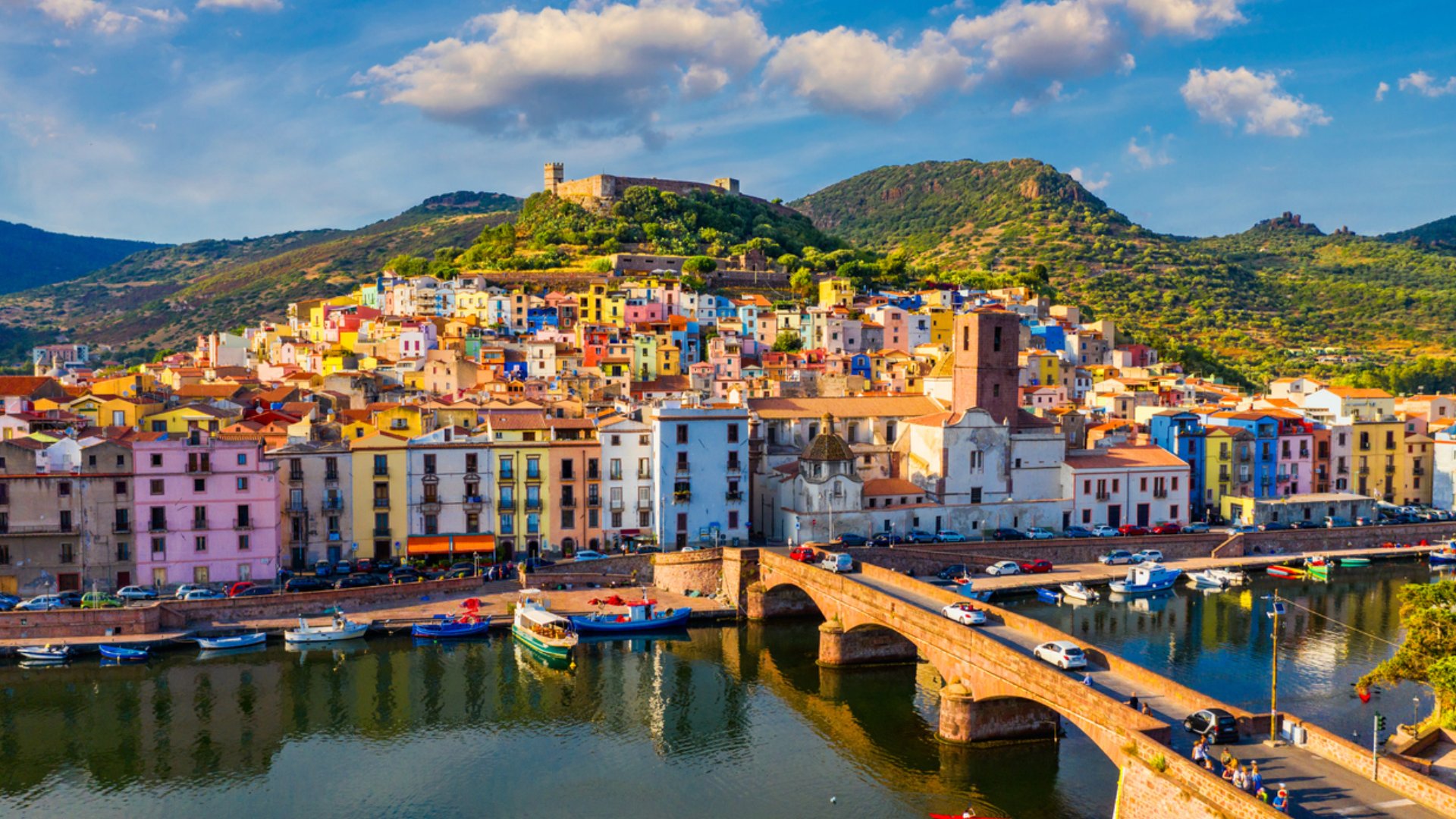Borgo costiero colorato con case sul lungomare e ponte sul fiume, vista panoramica.