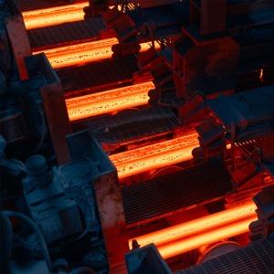 Barre di acciaio incandescenti in un impianto industriale di laminazione