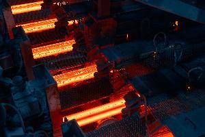 Barre di acciaio incandescenti in un impianto industriale di laminazione