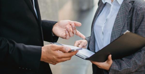 Due persone discutono con dei documenti e una cartella.