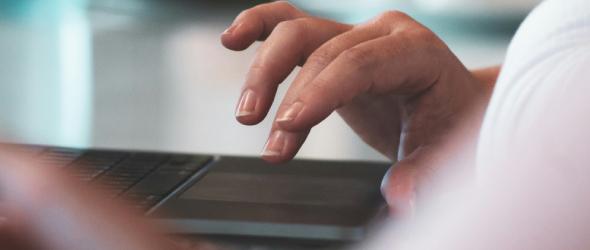 Una persona usa un portatile con le dita sul touchpad.