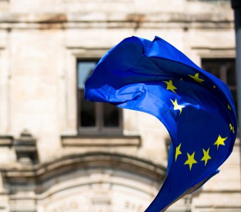 Bandiera dell'Unione Europea che sventola davanti alla facciata di un edificio in pietra