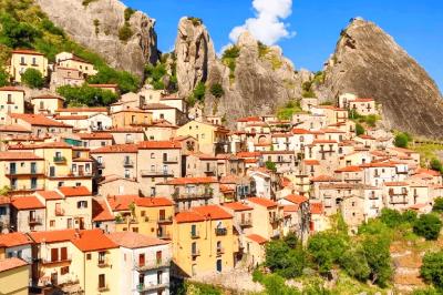 Vista di case con tetti in terracotta in un borgo montano, circondato da rocce e montagne.
