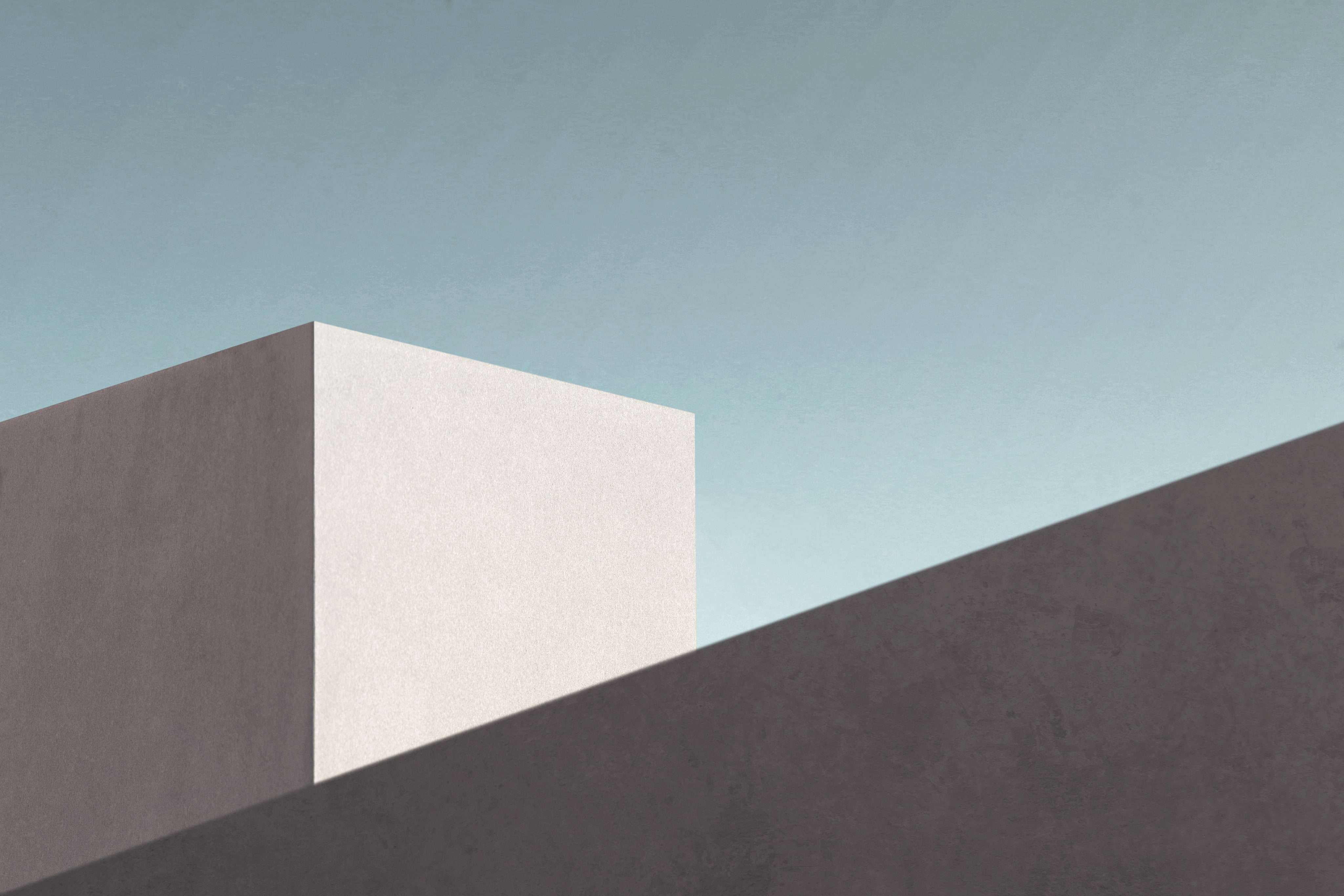 Facciata di edificio architettonico minimalista con colori smorzati sotto un cielo terso.