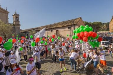 Festa all’aperto in una piazza con bambini e palloncini colorati davanti a un edificio storico.
