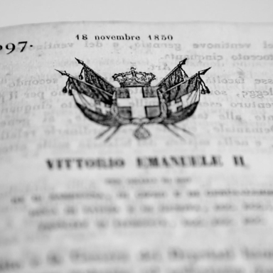 Copertina di un documento storico stampato in bianco e nero con testo in italiano e un piccolo stemma/illustrazione centrale