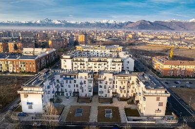 Complesso di social housing con edifici residenziali moderni e vista sulle Alpi