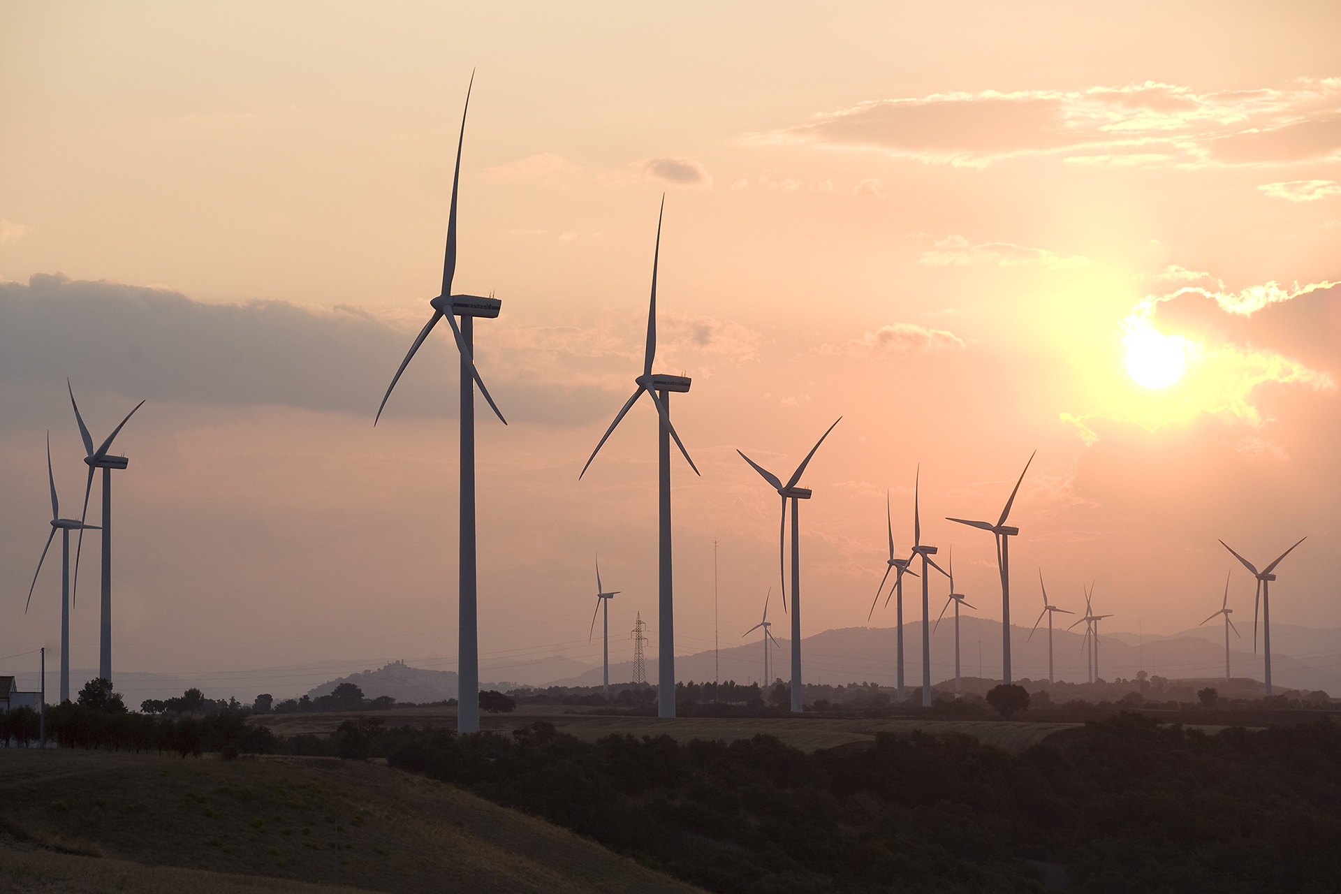Parco eolico al tramonto con turbine sul paesaggio.