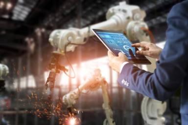 Tecnico industriale con tablet che controlla un impianto mentre avvengono scintille e lavori.