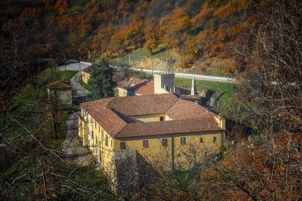 Antico monastero giallo con tetti in terracotta immerso nei boschi autunnali.