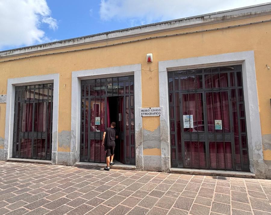 Ingresso di un museo civico fotografico in un edificio giallo con porte e finestre protette da grate.