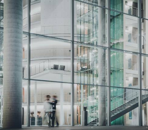 Interno di un edificio moderno con uffici e corridoi, visti attraverso vetrate e strutture in metallo