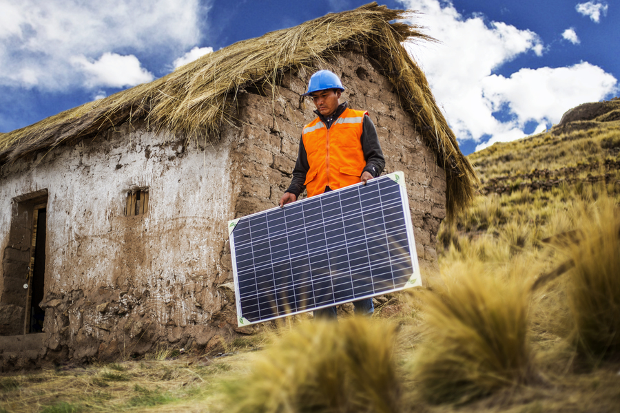 Operaio che installa un pannello solare vicino a una casa rurale.