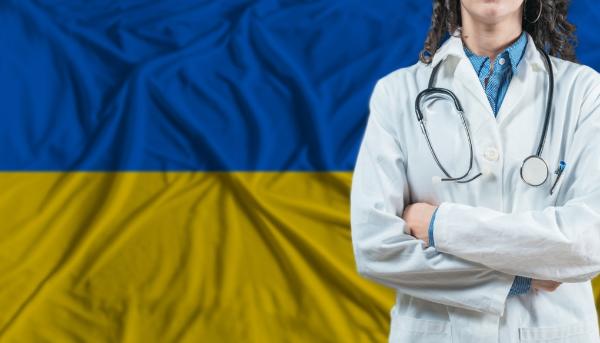Donna con camice da medico di fronte a bandiera ucraina